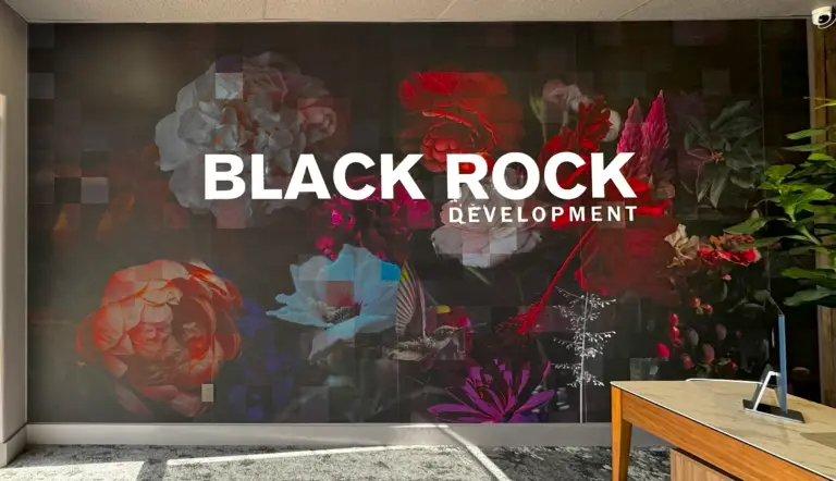 A Mural of Black Rock Development's Logo with a background of different flowers, placed on a wall inside an office.